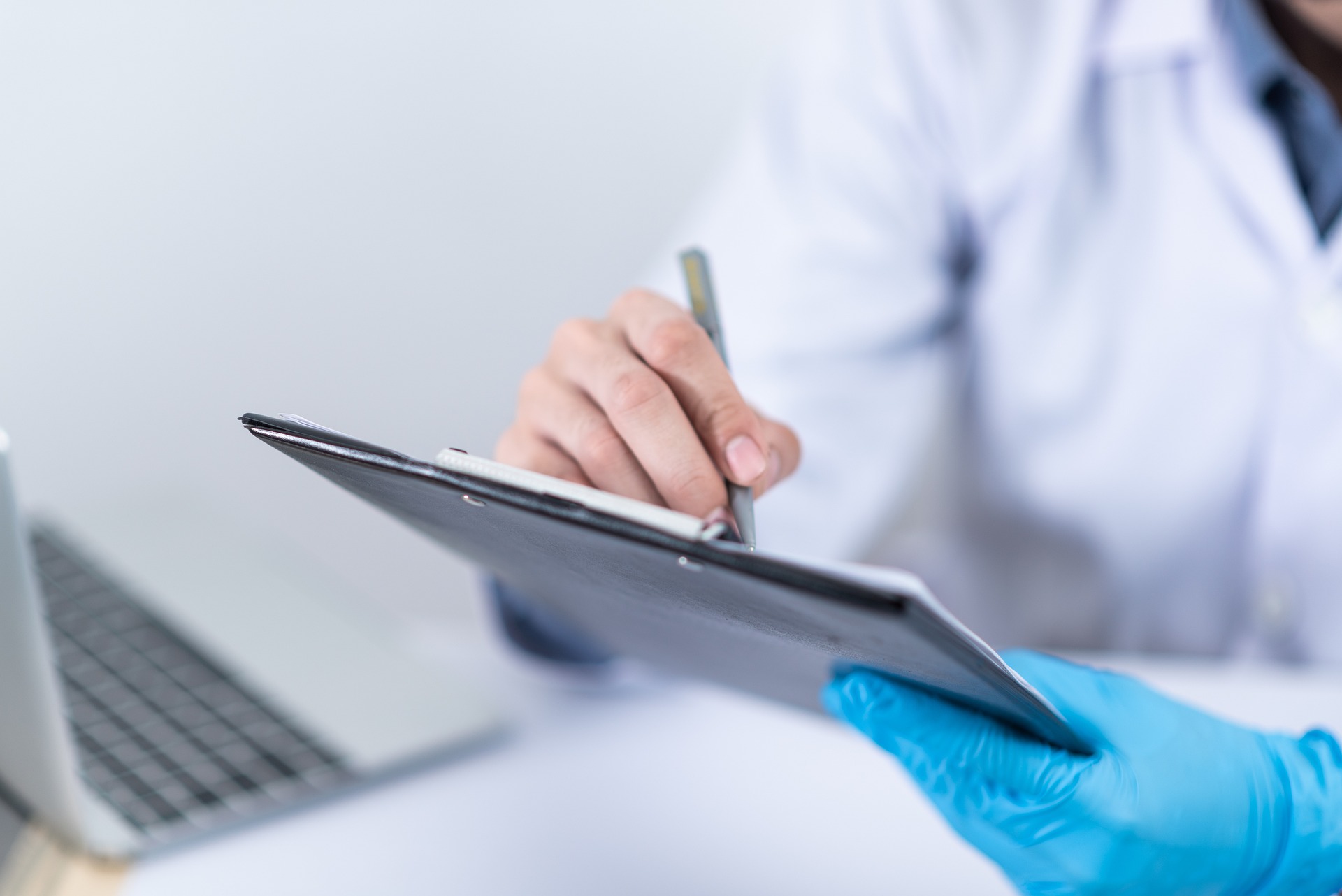 Research Professionals CRO clinical researcher in white lab coat uses digital tablet to assess clinical study data.