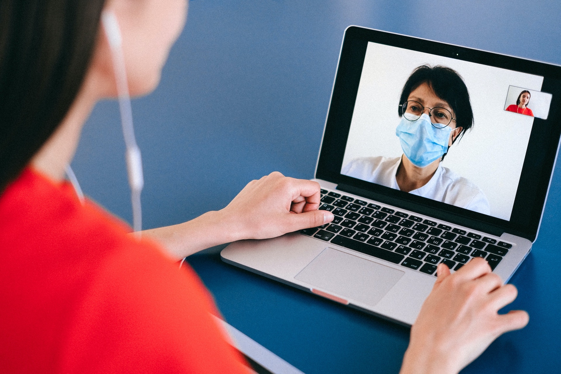 Doctor speaking with home nurse wearing mask on computer video call for DCT